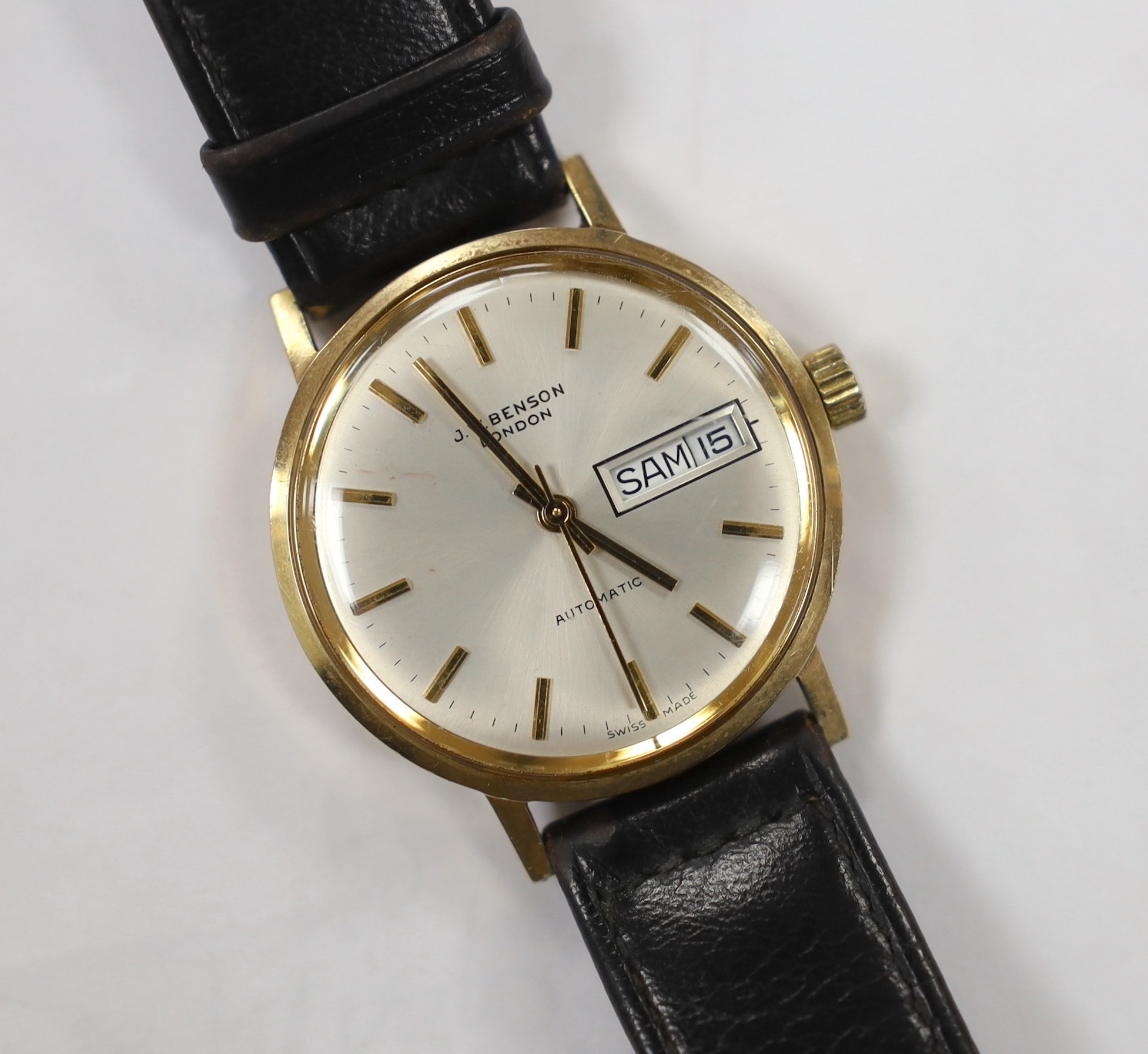 A gentleman's yellow metal (Swiss 9ct mark) J.W. Benson automatic day(in French & English)/date wrist watch, on associated strap, case diameter 34mm, gross weight 36.8 grams.